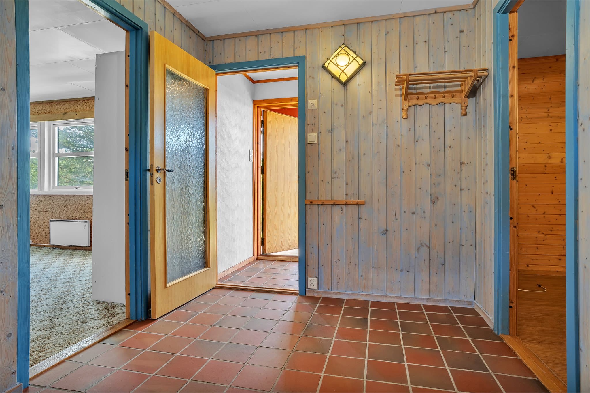Hallen har flislagt gulv og panelte vegger.