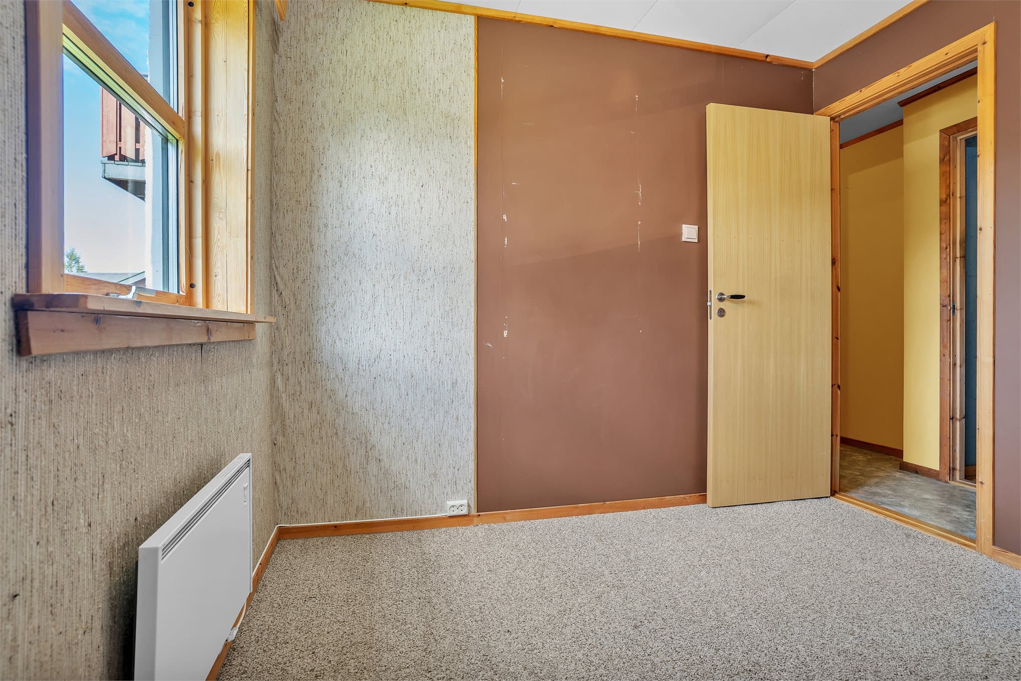 Innredet rom i underetasjen med teppe på gulv og vindu mot hagen.