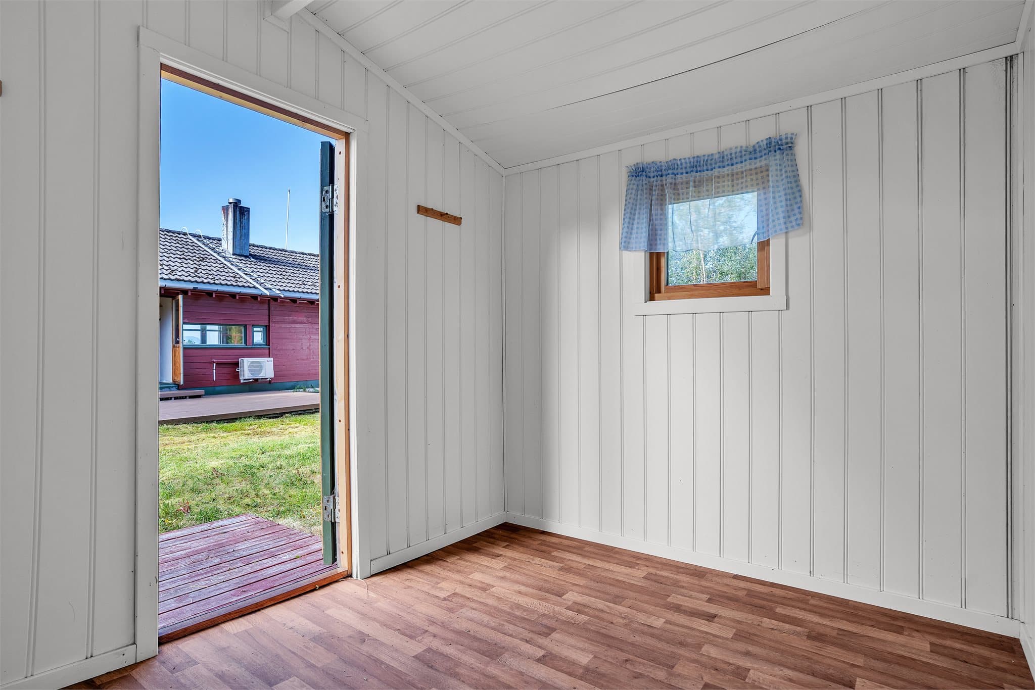 Uthuset har en innredet del med malte plater og vindu ut mot hagen.