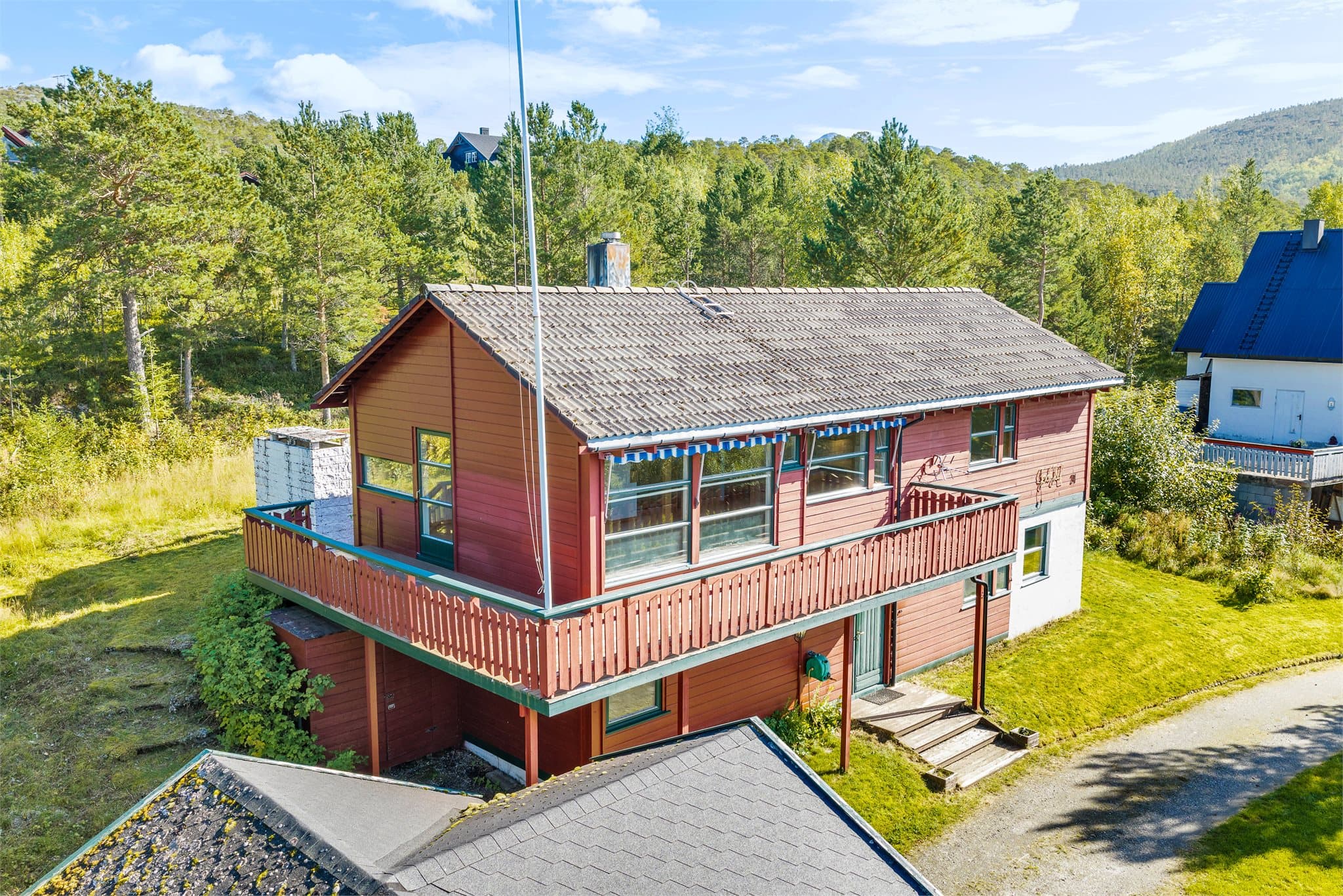 Boligen og uteplassene er omgitt av gressplen og frodig naturtomt.