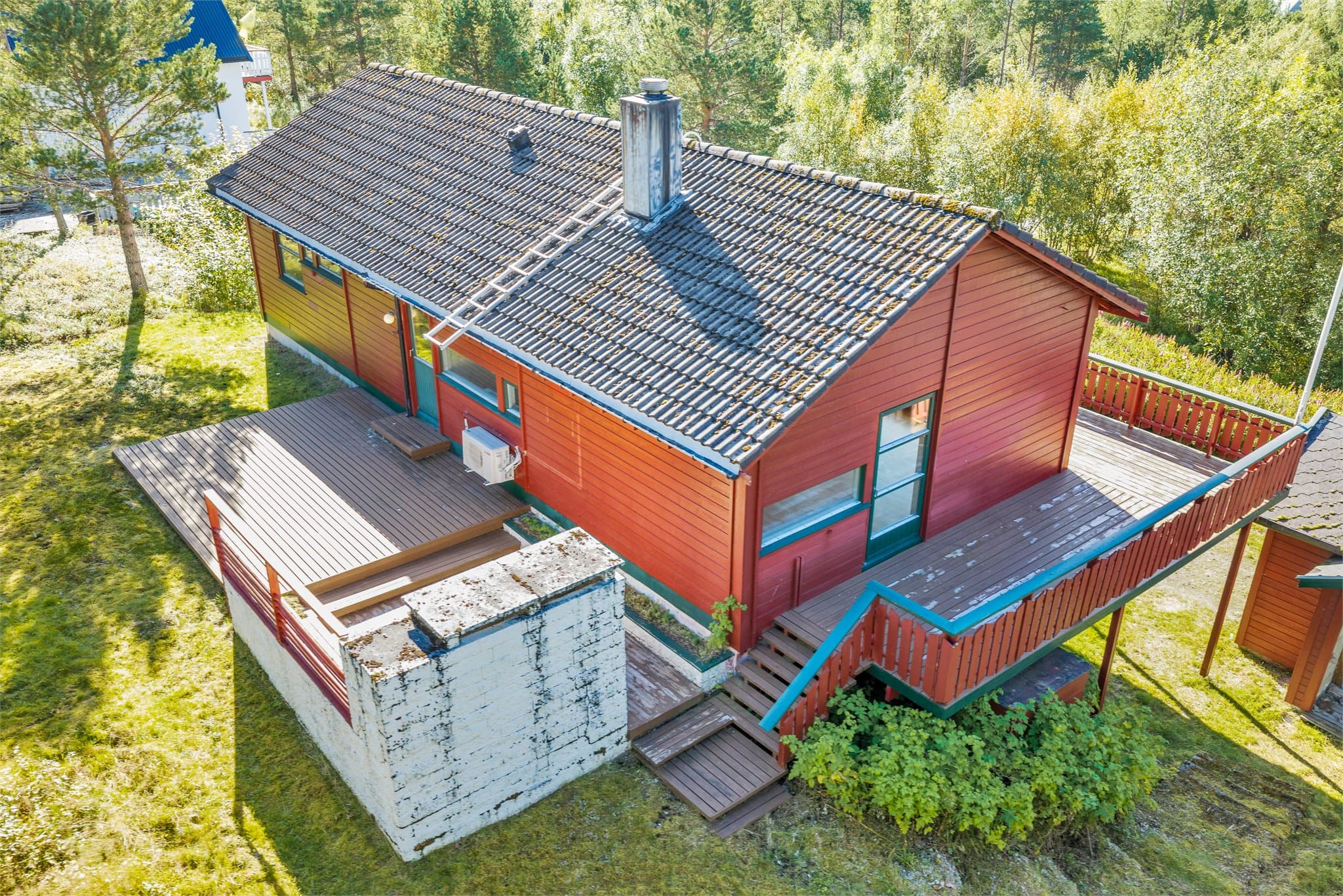 Baksiden av boligen har en skjermet beliggenhet mot naturtomt og trær.