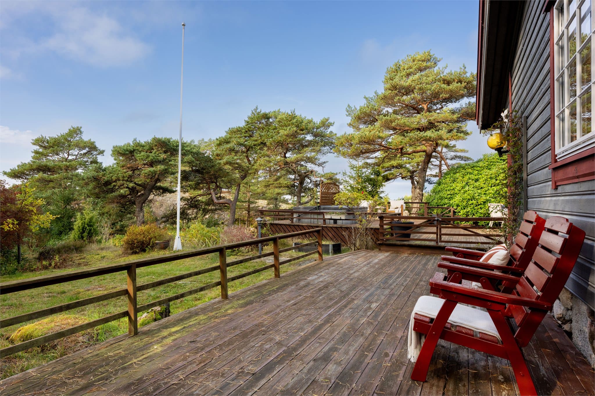 Terrasse i trekonstruksjon med rekkverk oppført langs hytta.