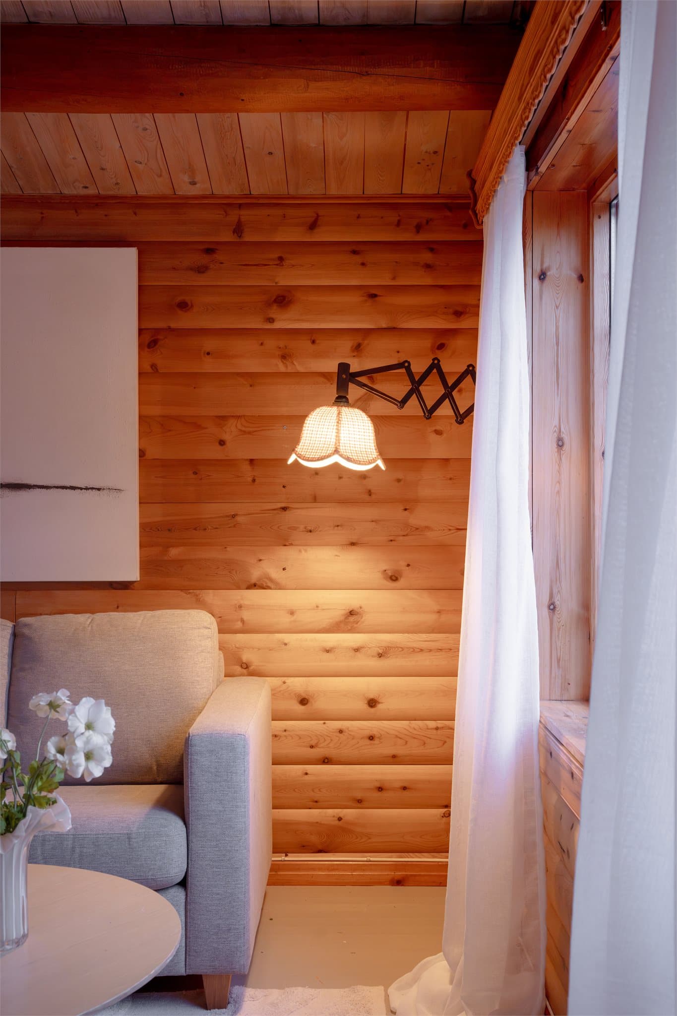Vegglampe montert på laftet tømmervegg.