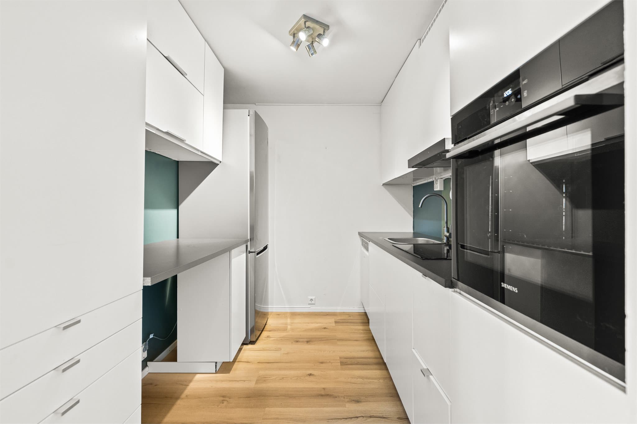 Separat kjøkken. Innredningen har tidløse, glatte fronter kombinert med laminatbenkeplate og nedfelt oppvaskkum med ett- greps armatur. Her er det godt med skap- og benkeplass, samt overskap som gir ekstra oppbevaring.