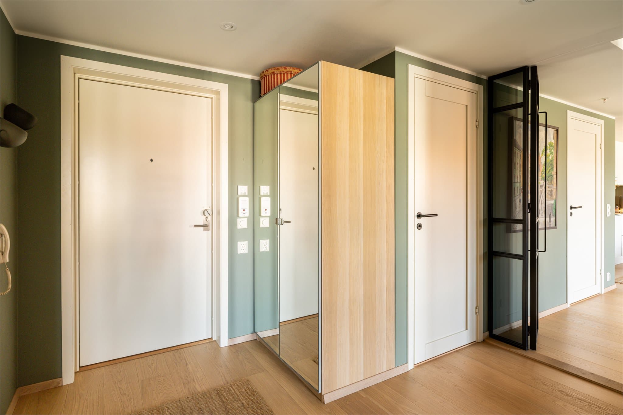 Leiligheten har en innbydende entré med god plass til oppbevaring og avkledning. Veggene er malt i en dus grønn tone som gir et lunt og moderne uttrykk, kombinert med lyse gulvflater som bidrar til en harmonisk helhet.