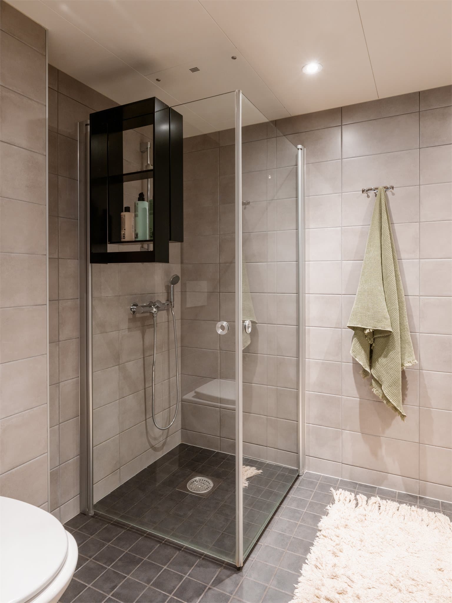 Dusjen er plassert på gulv bak innfellbare dører i herdet glass.