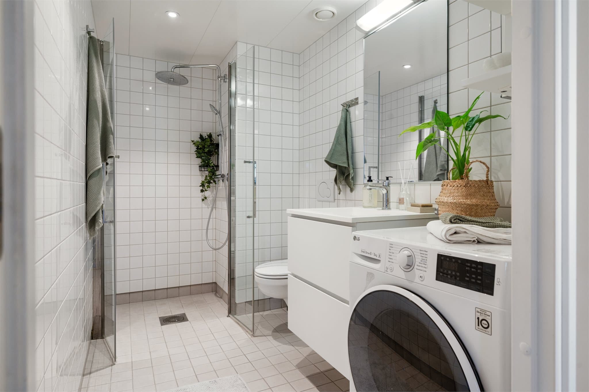 Baderommet har vegghengt toalett, dusjhjørne og opplegg for vaskemaskin.