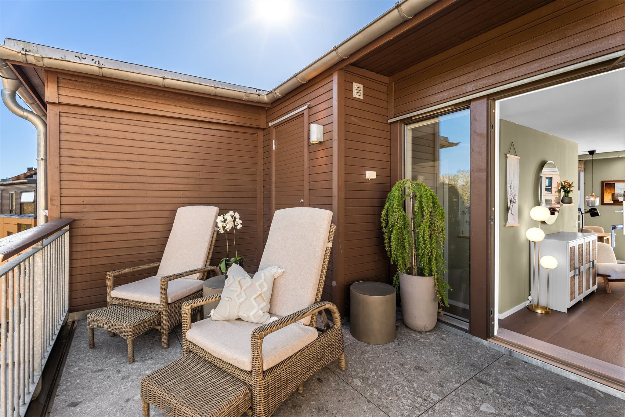 Den østvendte verandaen har flislagt dekke og en praktisk utebod, begge deler nytt fra 2024.