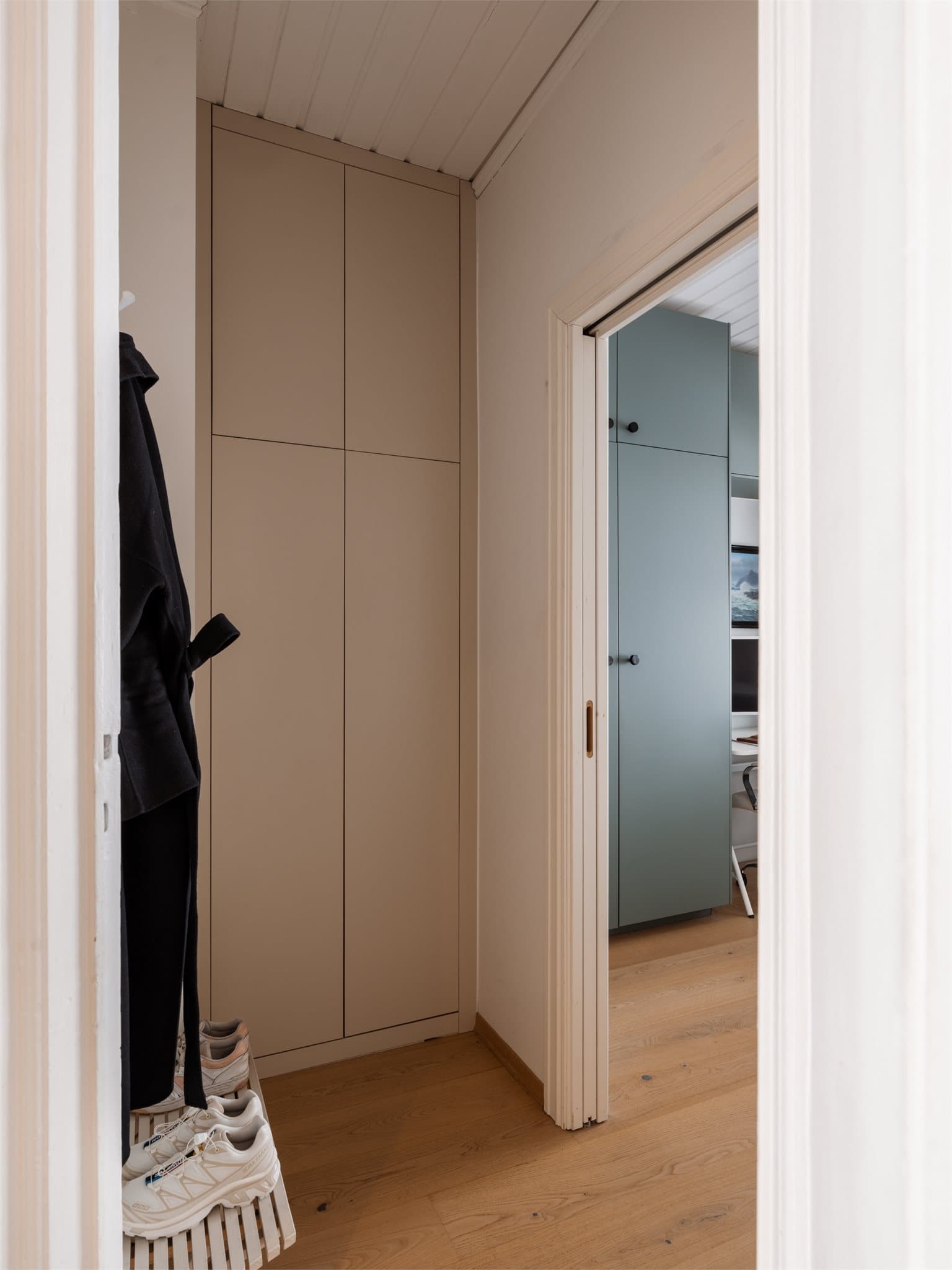 Delikat og plassbygget skap i gangen med skjult opplegg for vaskemaskin på innsiden.