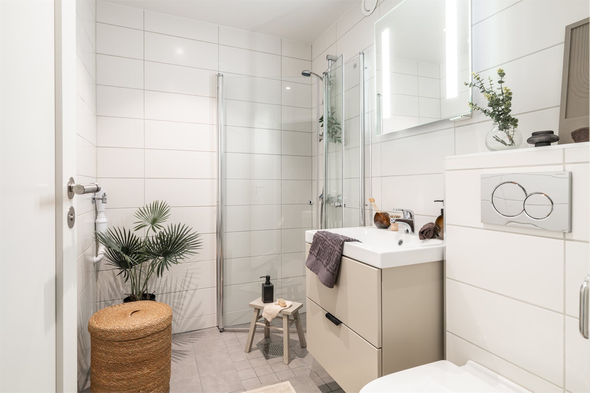 Lekkert flislagt bad fra 2023 med 20x20 fliser på gulvet og hvite 20x40 fliser på veggene.