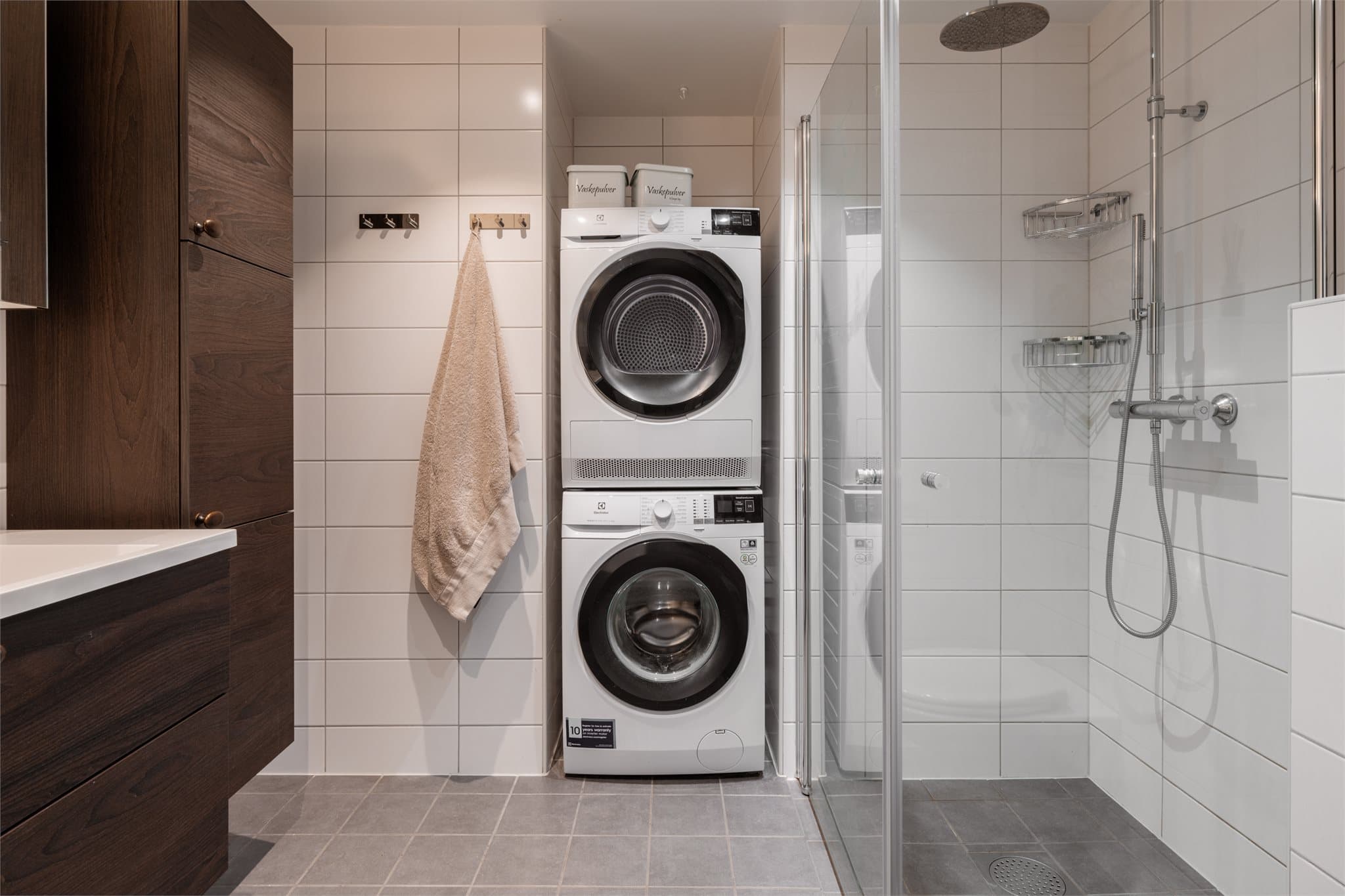 Badet har en elegant kombinasjon av lyse fliser og mørk, delikat innredning.