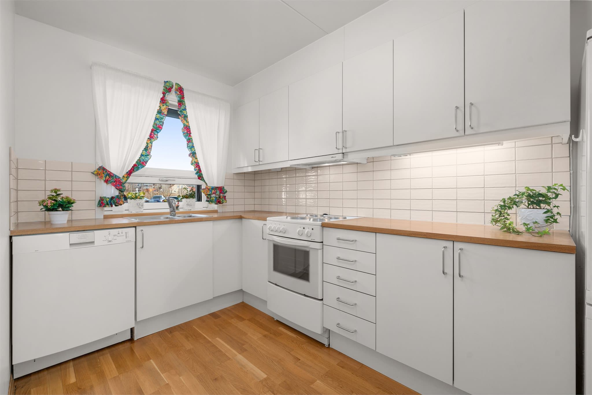 Kjøkkenet er stilrent med hvitmalt innredning og plass for frittstående hvitevarer.