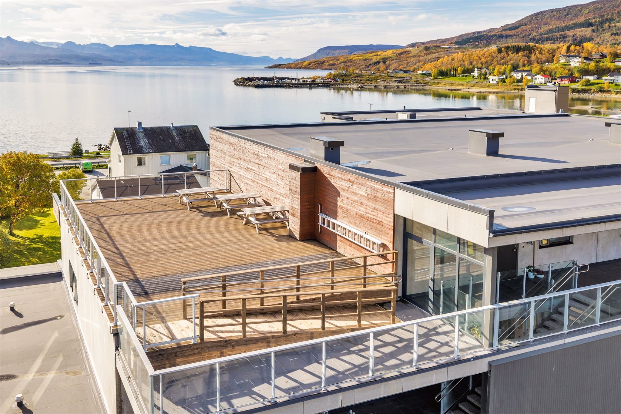 Felles takterrasse med sittebenker og åpen utsikt mot Herjangsfjorden og småbåthavnen.