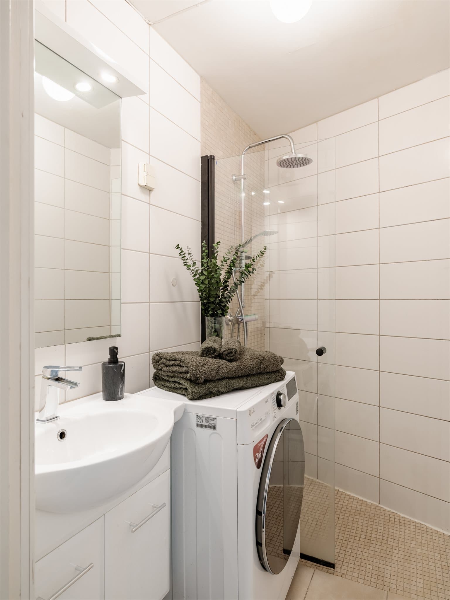 Lyst, flislagt baderom med opplegg for vaskemaskin.