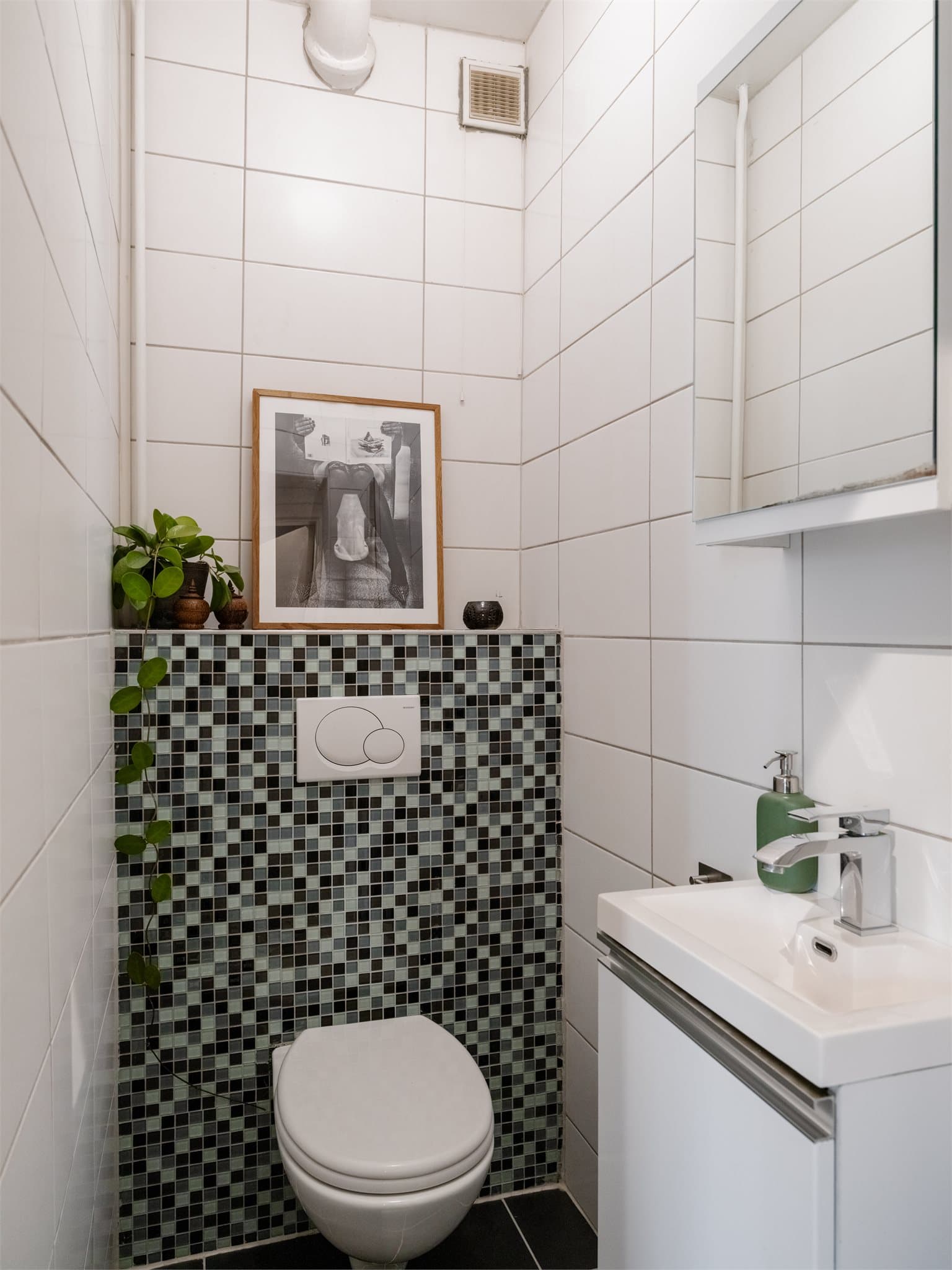 Toalettrom med flislagte overflater på gulv og vegger, vegghengt klosett og servant.