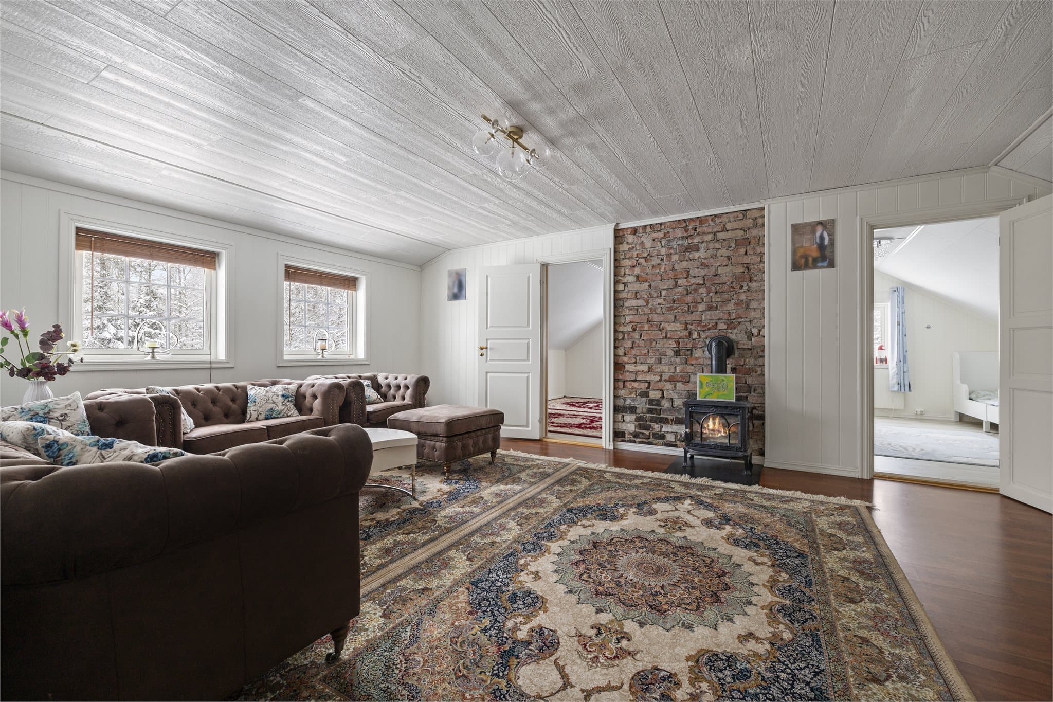 Den eksponerte teglsteinsveggen bak ovnen er en markant detalj i rommet.