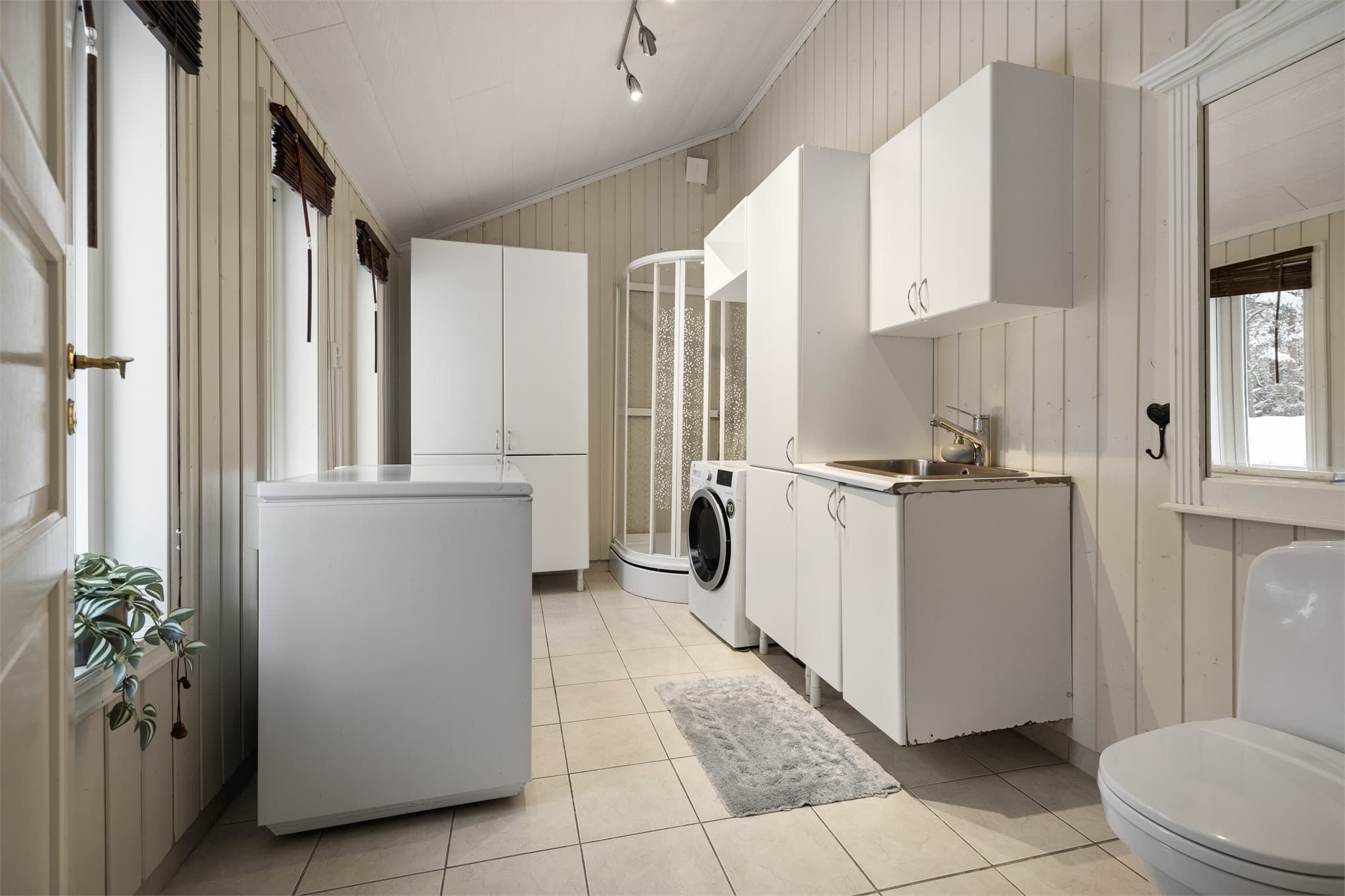 Praktisk vaskerom på 9 m² med flislagt gulv med elektriske varmekabler.