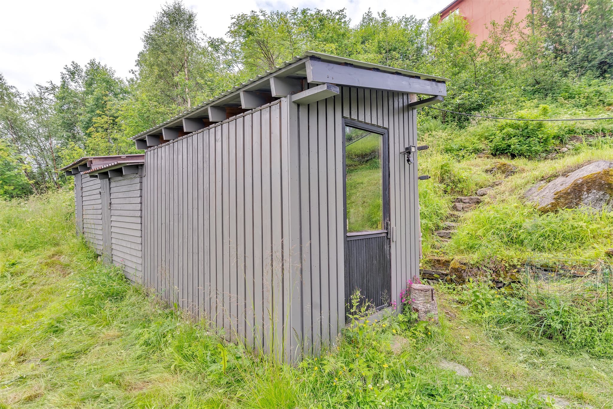 Uthus i trekonstruksjon med pulttak tekket med metallplater.