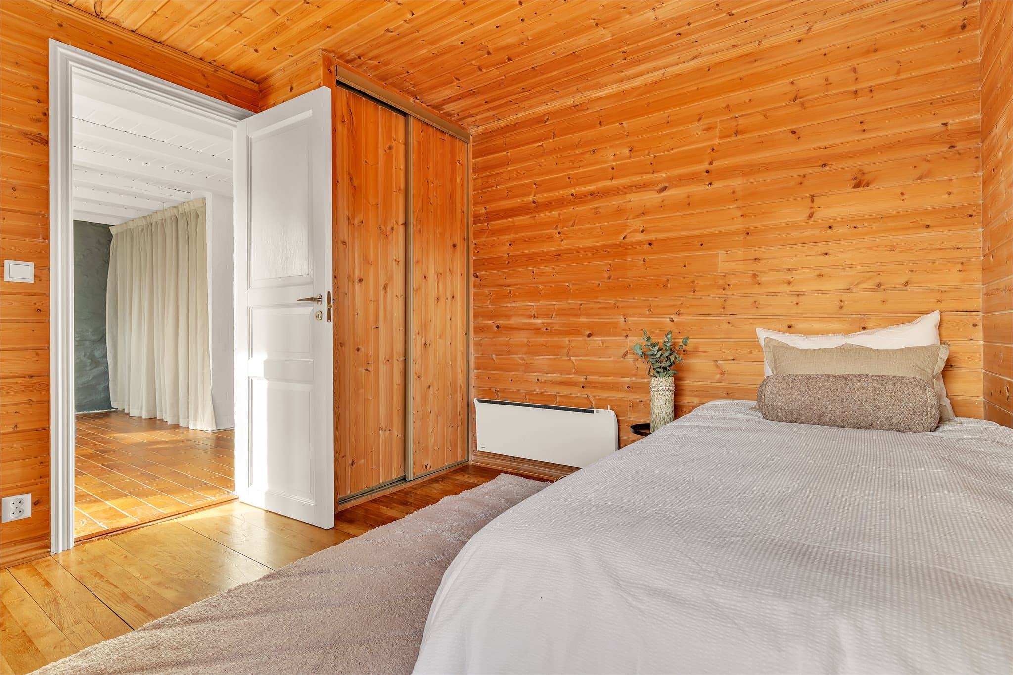 Rommet er utstyrt med skyvedørsgarderobe i furu og har dør mot entréhallen.