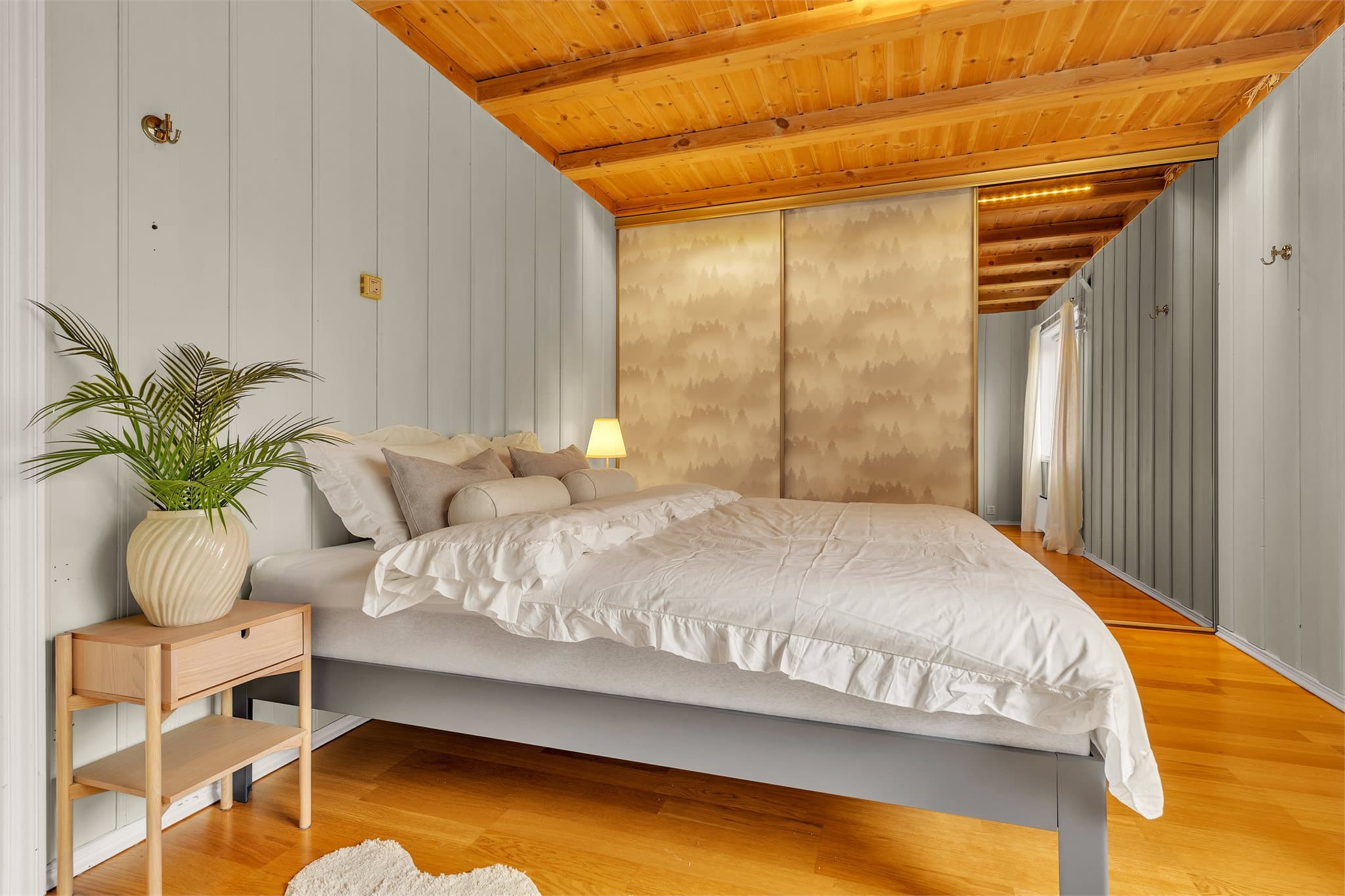 Rommet har skyvedørsgarderobe med dekorative fronter og panel i himling.