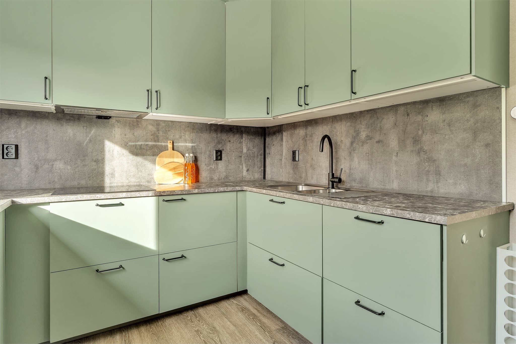 Kjøkkeninnredning fra IKEA fra 2021 med glatte salviegrønne fronter og laminatbenkeplate.