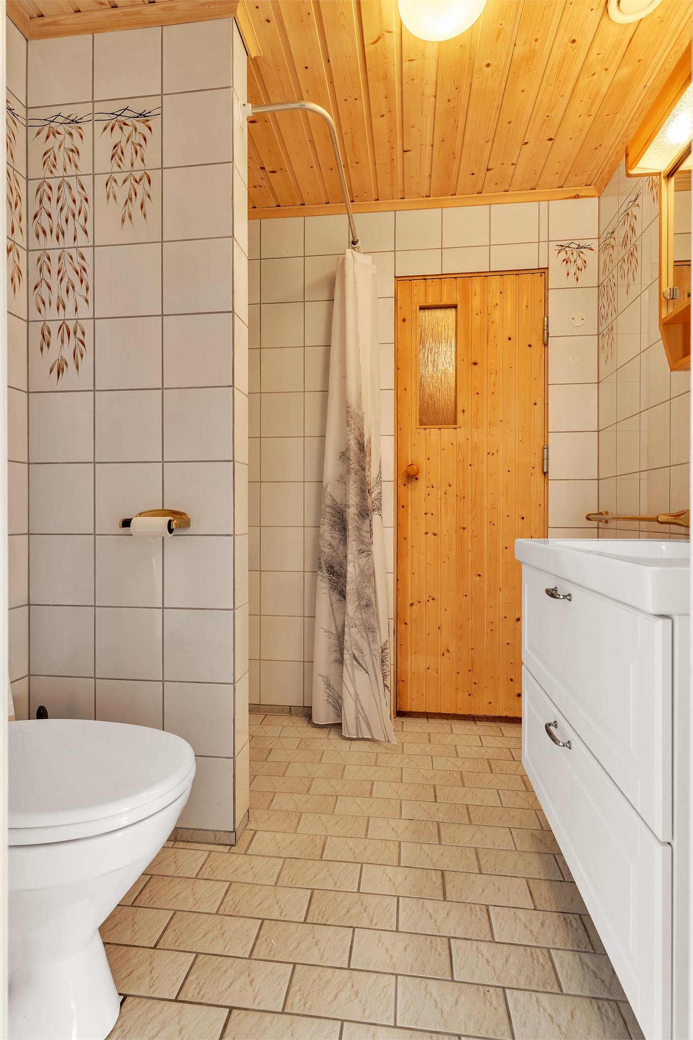 Baderomsinnredning med profilert front og dør med glassfelt inn til badstuen.
