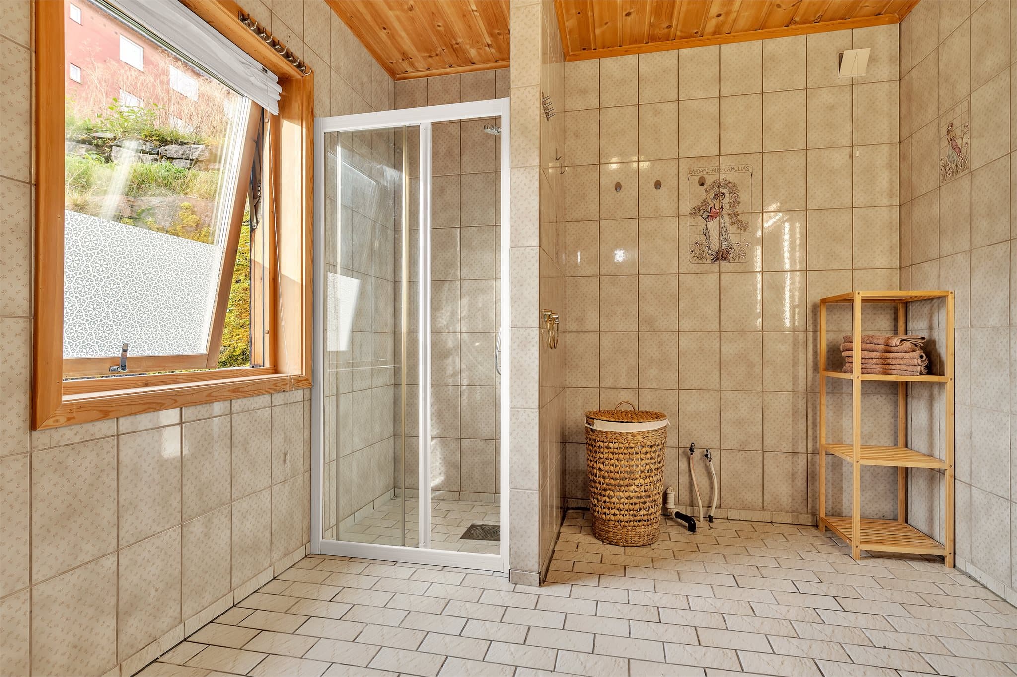 Badet har fliser på vegger, panel i tak og åpningsbart vindu.
