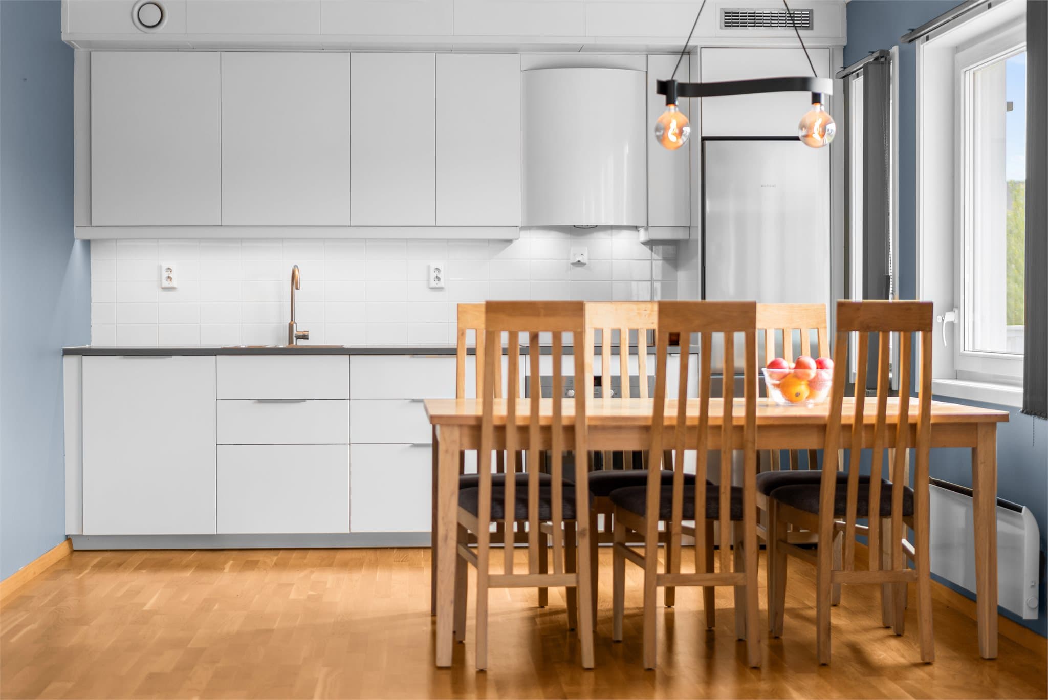Kjøkkeninnredningen har hvite, slette fronter og laminat benkeplate.