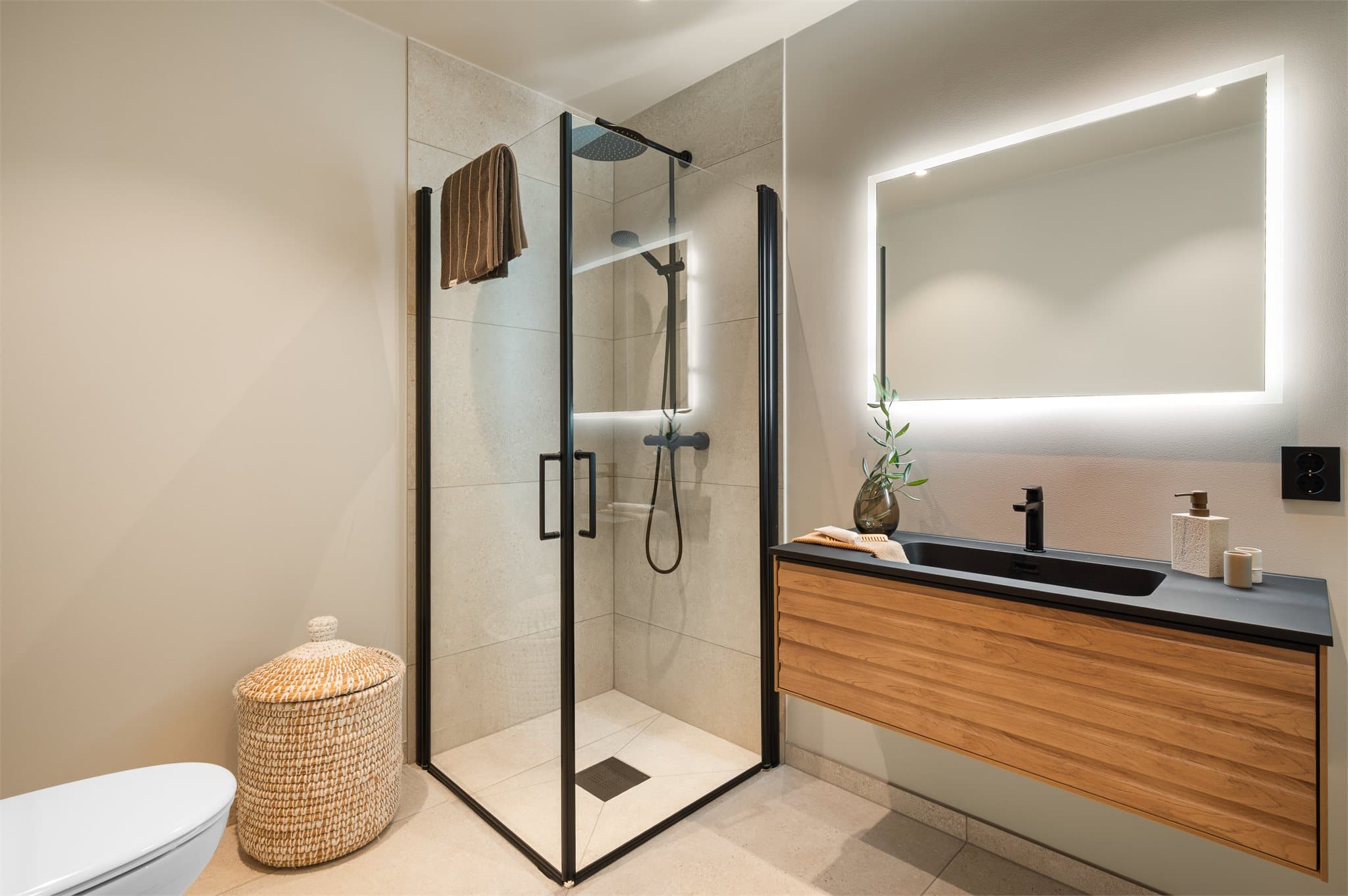 - Badet er innredet med speil m/ belysning, vegghengt toalett, dusj og benkeskap m/ servant -