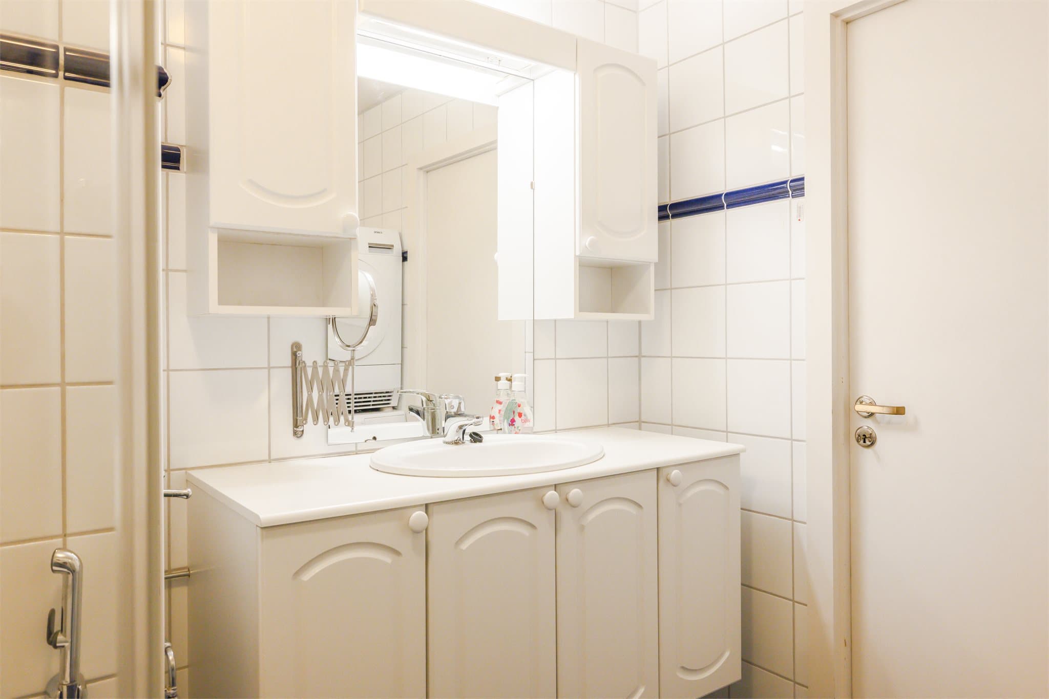 Badet har varmekabler i gulv, og er innredet med hvit profilert baderomsinnredning med nedfelt servant i laminat benkeplate, toalett og dusjhjørne med innfellbare glassvegger.