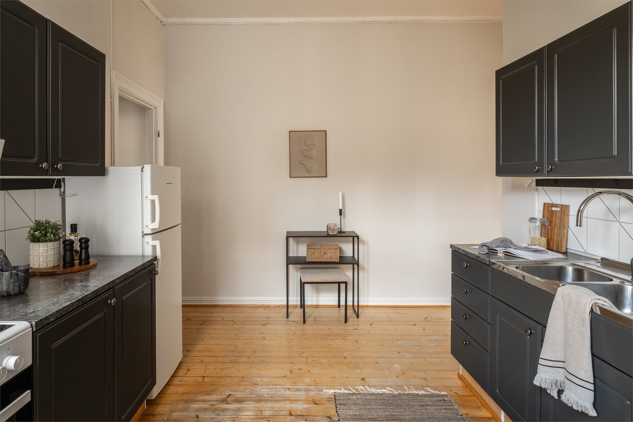 Innredning med profilerte, malte fronter. Laminat benkeplate med nedfelt kum i rustfritt stål.