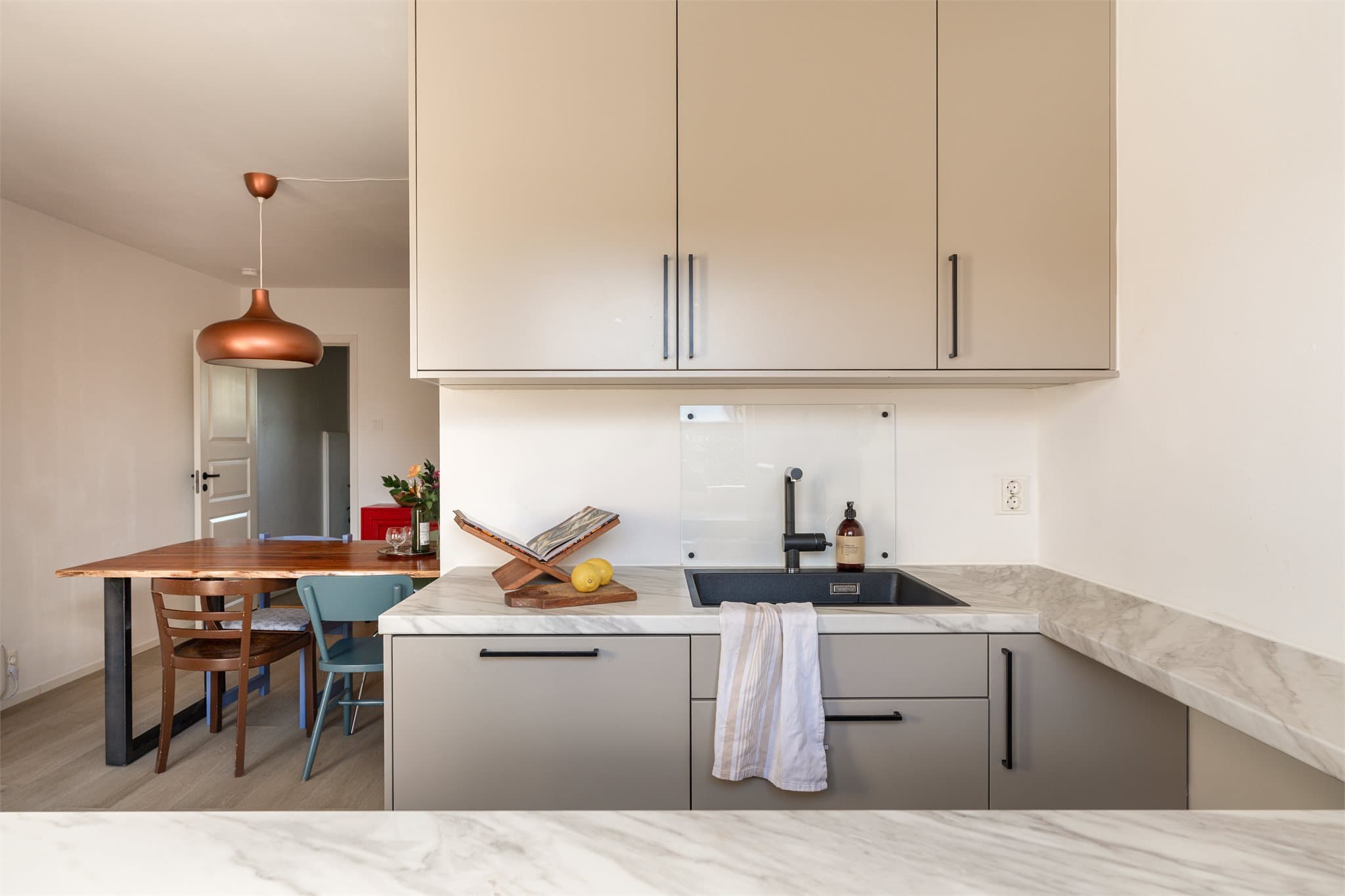 Kjøkkenet har slette fronter i et behagelig farge palett, med en nydelig laminat benkeplate med marmor look!