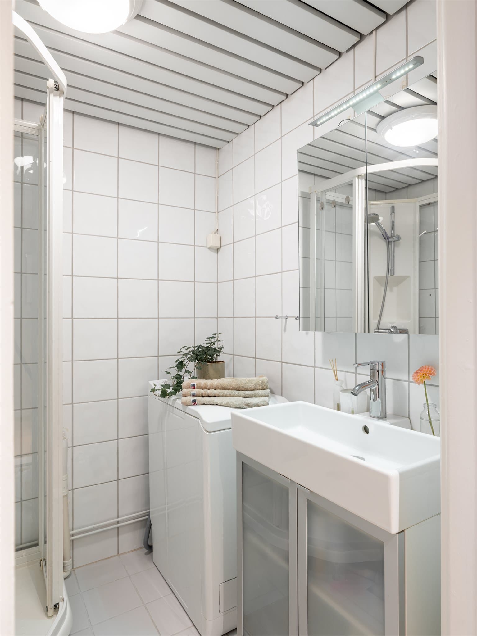 Flislagt bad innredet med servant, underskap og opplegg for smal vaskemaskin.