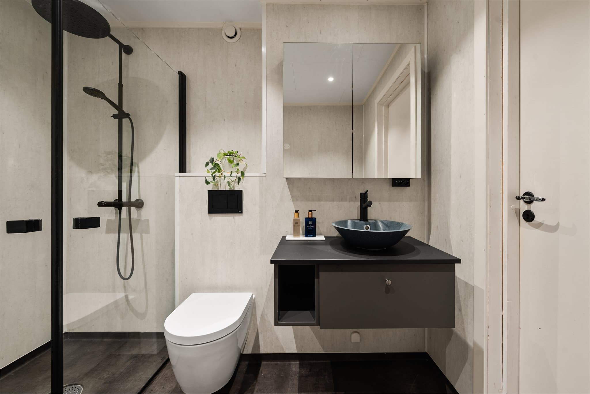 Lekkert baderom med våtromsplater på vegg og belegg på gulv.