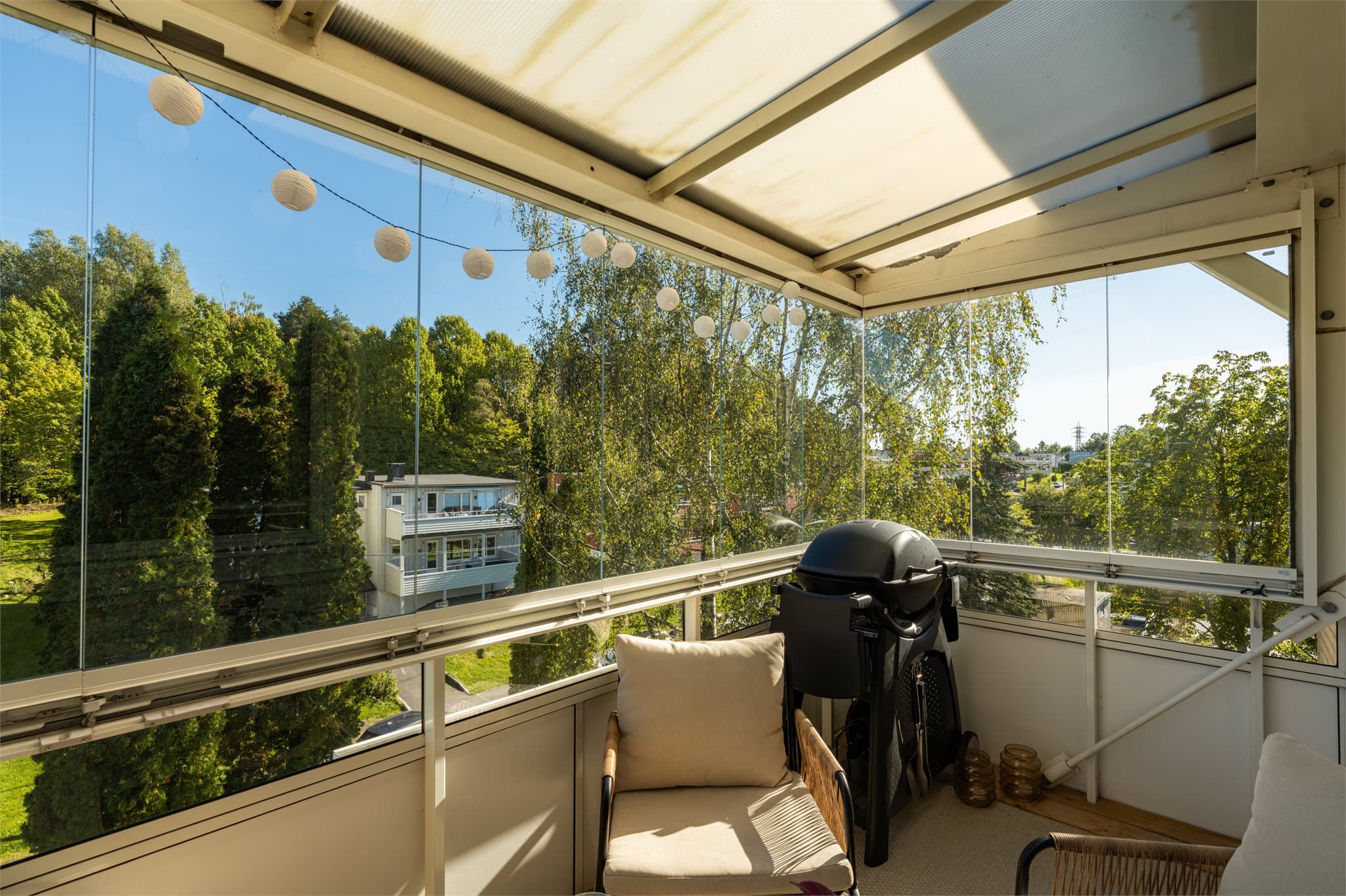 Fra stuen er det direkte utgang til balkongen, noe som gir en naturlig forlengelse av oppholdsarealet. Glasspanelene kan skyves til side for å åpne opp på varme dager.