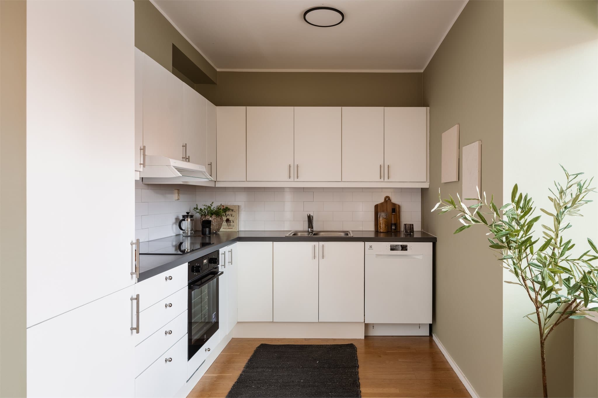 Moderne kjøkken med hvit innredning, grå laminatbenkeplate og integrerte hvitevarer fra 2026.