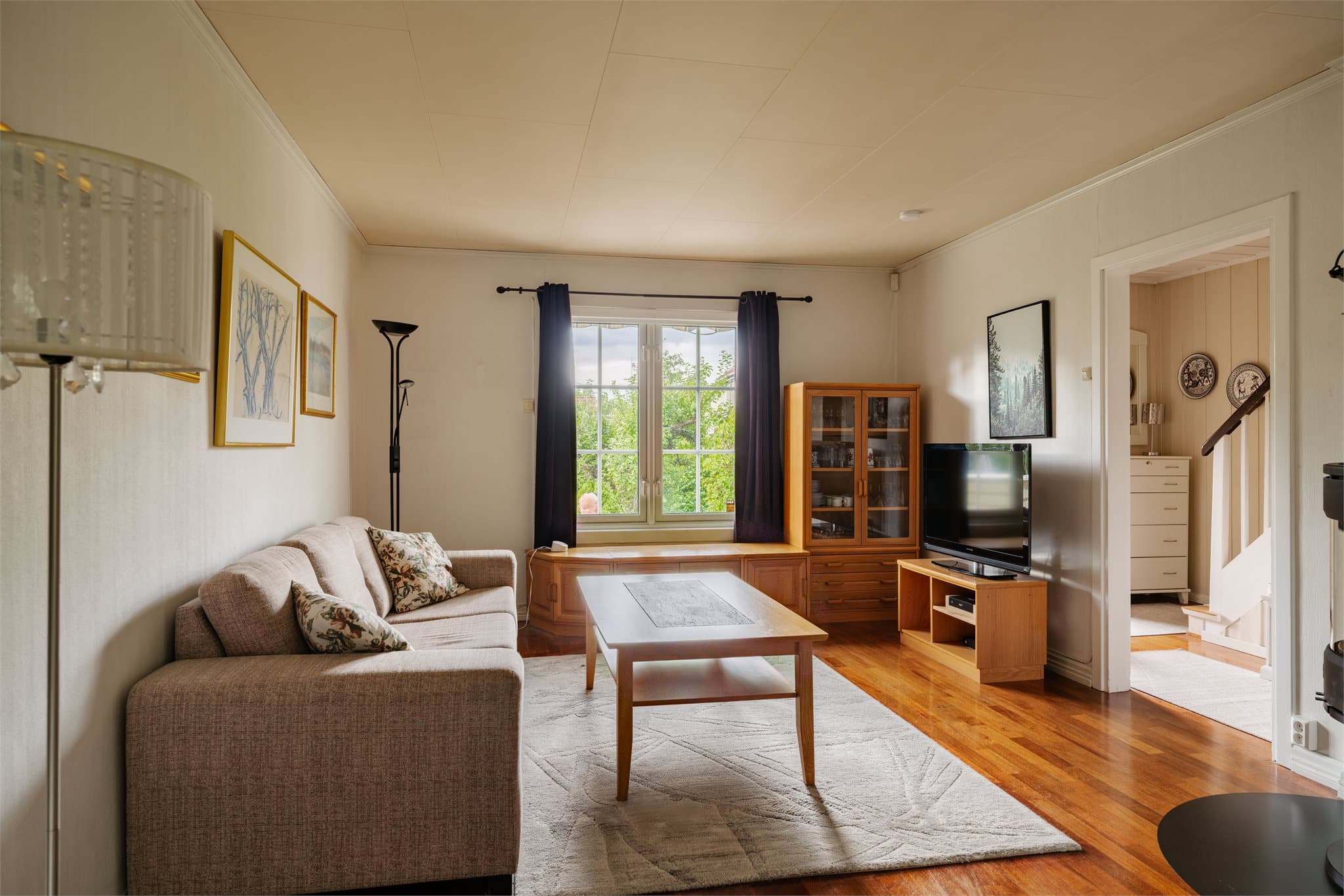 Stuen har plass til sofagruppe og har overflater med parkett og malt strie.