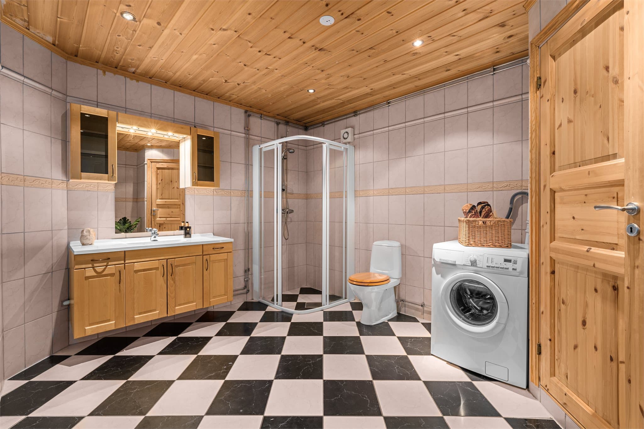 Stort flislagt bad med opplegg for vaskemaskin.