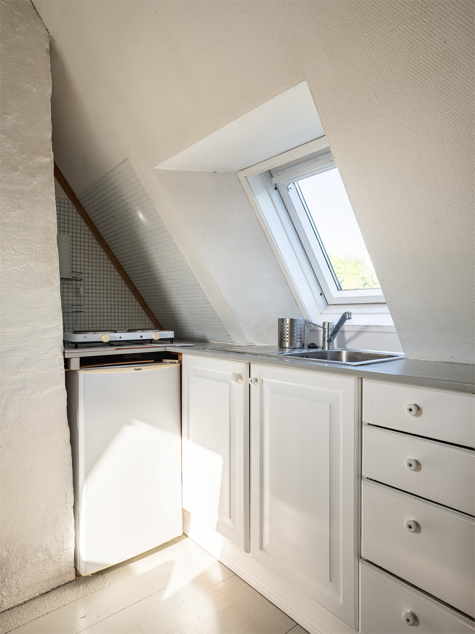 Kjøkkeninnredning med glatte fronter og benkeplate i tre. Fra kjøkkensiden har man utsikt mot Harald Hals park.