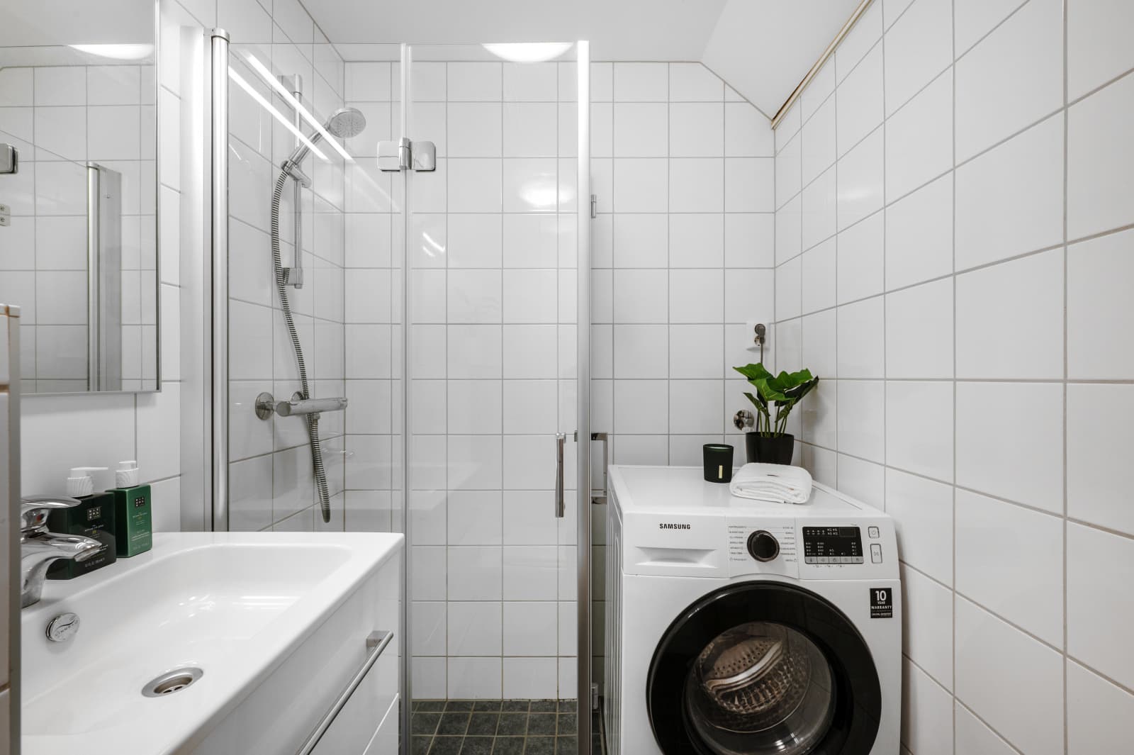 - Badet inneholder vegghengt toalett, benkeskap med servant, dusjdører i glass, opplegg for vaskemaskiin og fordelerskap til "rør i rør" vannforsyning -