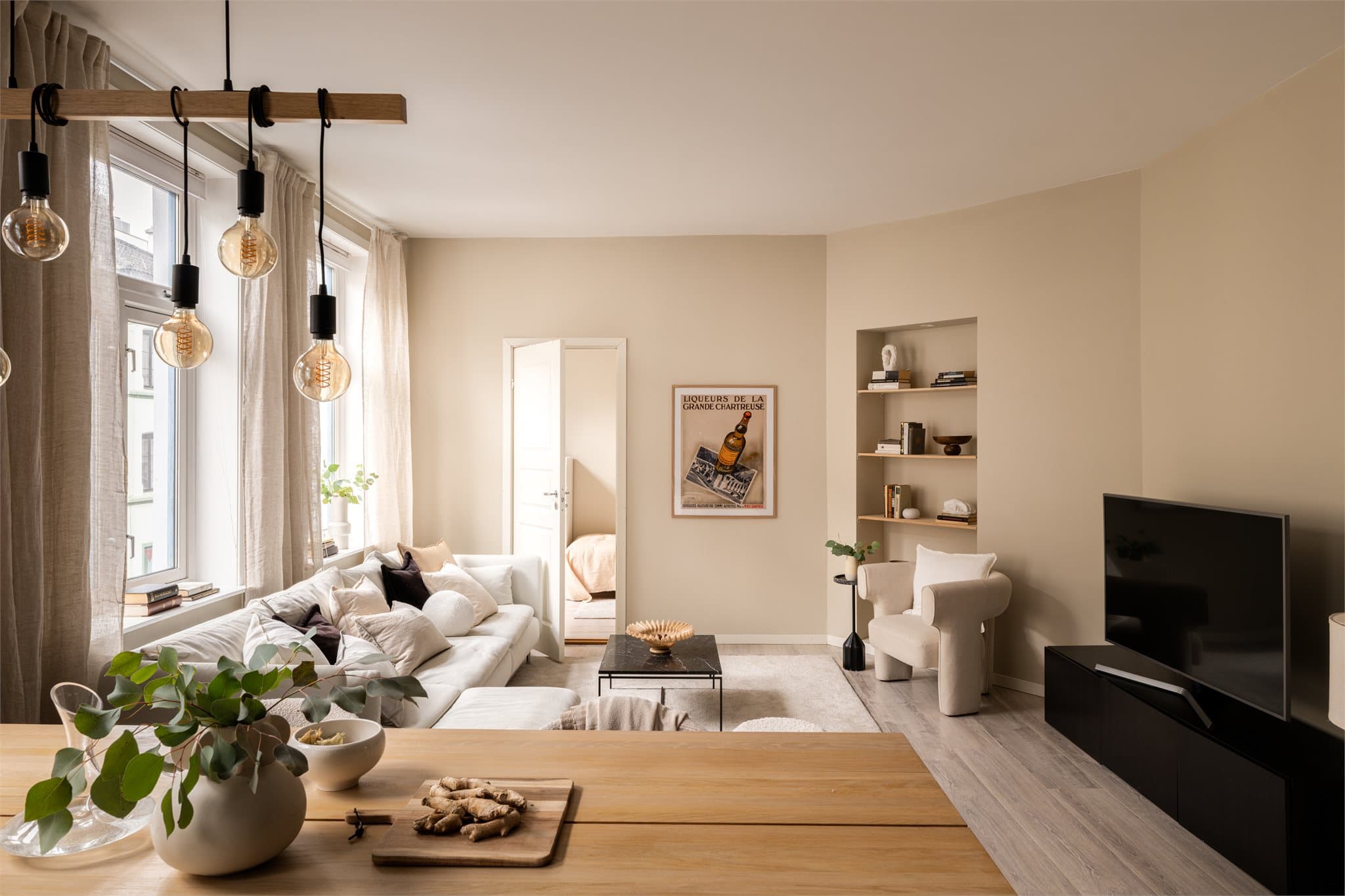 Stuen er lett å møblere med god plass til både sofagruppe og spisebord. En innfelt hylle-nisje gir en stilren oppbevaringsløsning.