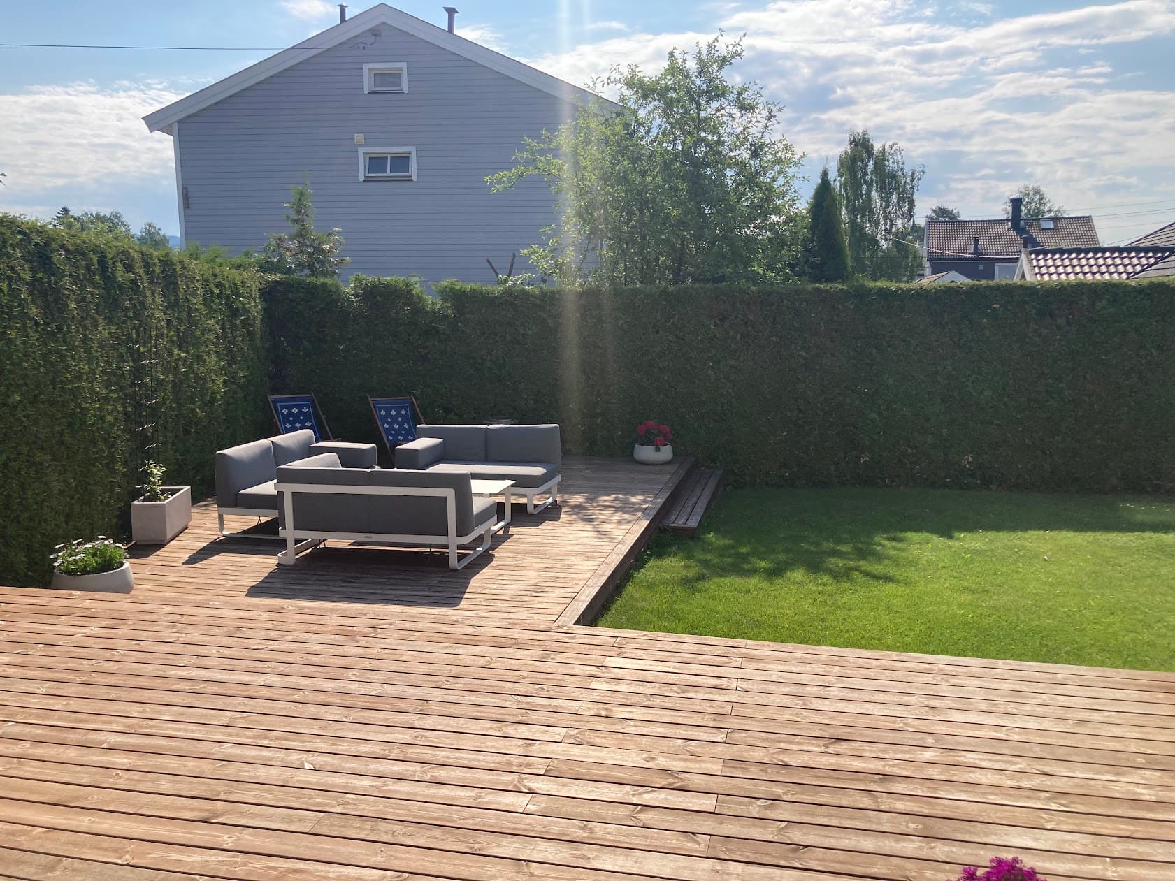 Selgers sommerbilde. Den sørvendte terrassen på 85 m² ble anlagt i 2021 og har trapp ned til hagen.