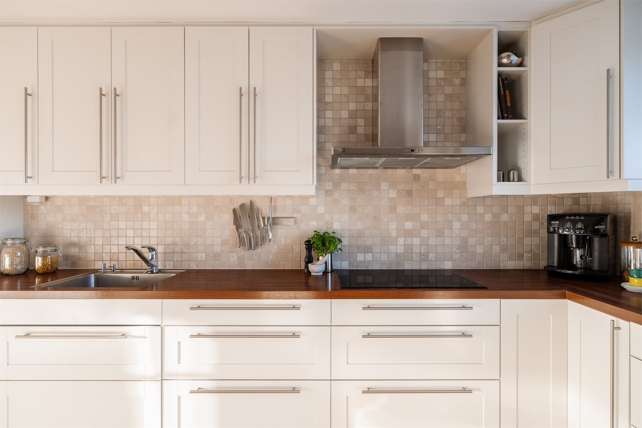 Laminatbenkeplate med planlimt kum i rustfritt stål og flislagt vegg over benken.