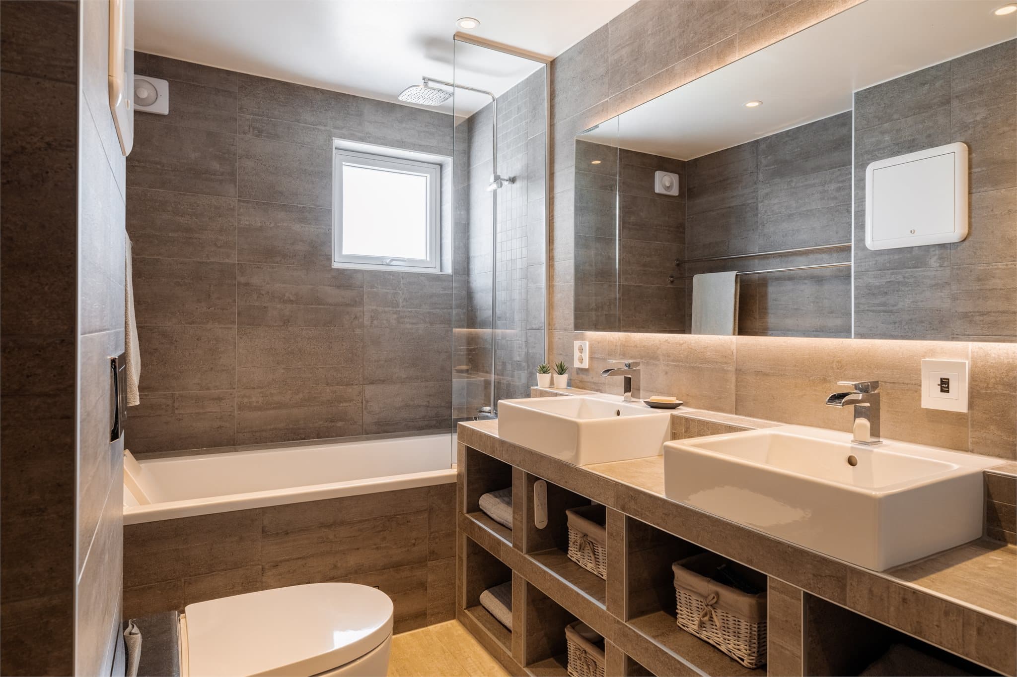 Badet har en plassbygget, flislagt servantløsning med hyller og to toppmonterte servanter.