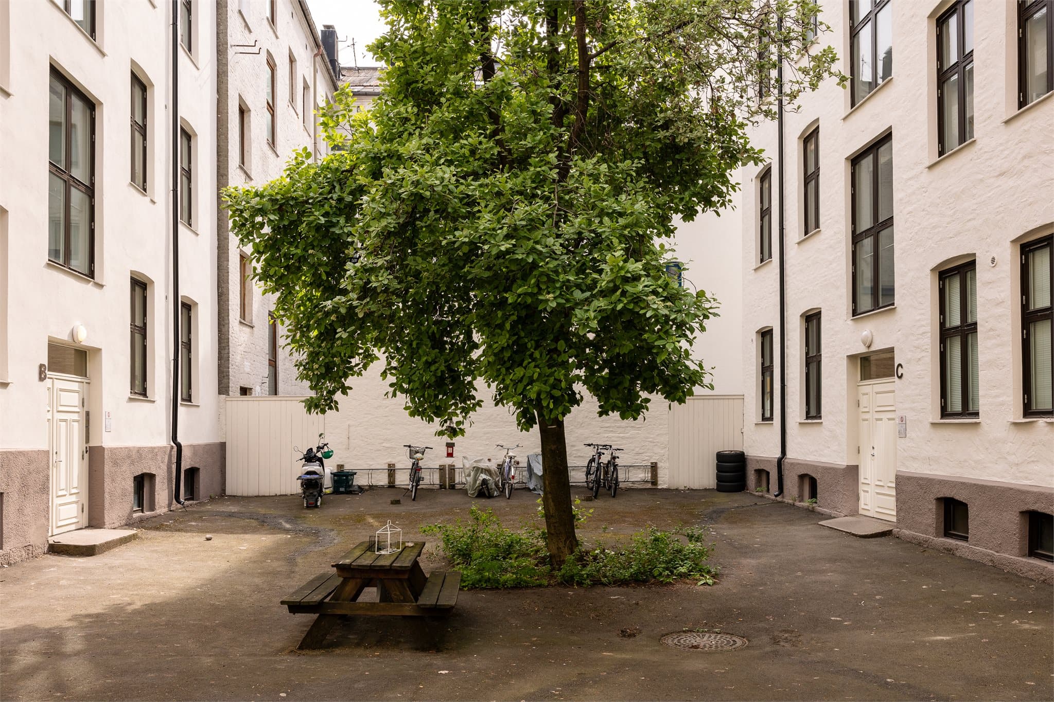 Lukket bakgård med sykkelstativ og sittebenk.