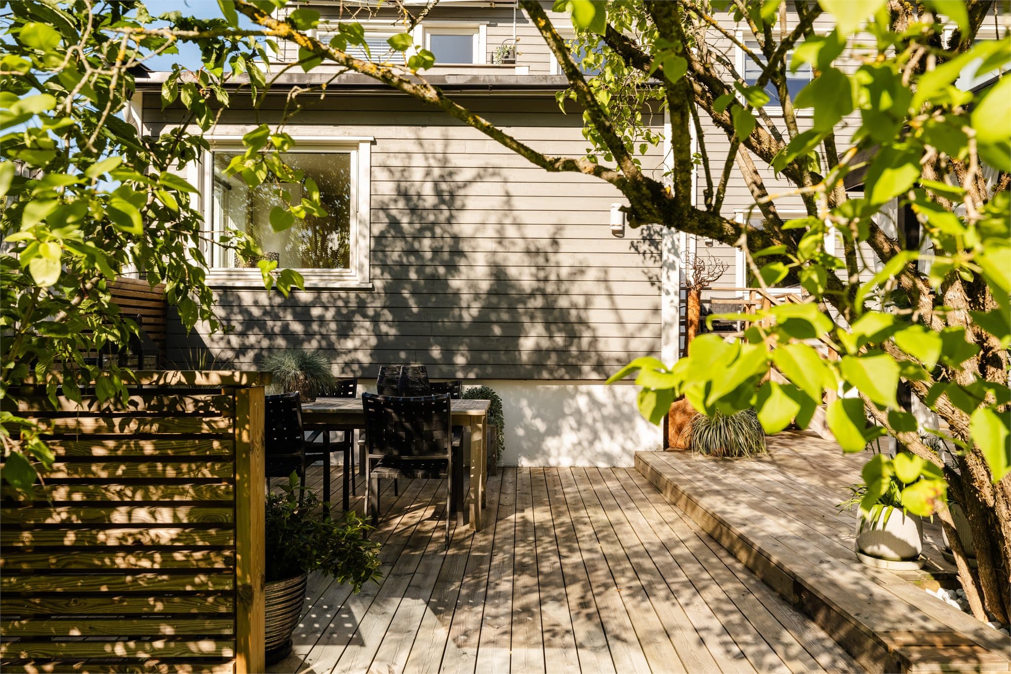 Tett og frodig beplantning rammer inn uteplassen og skaper private rammer.