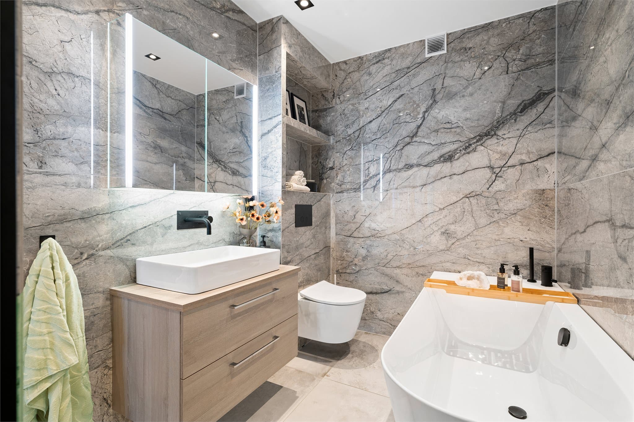 Badet har flislagte vegger med storformat fliser som gir et luksuriøst og helhetlig inntrykk.