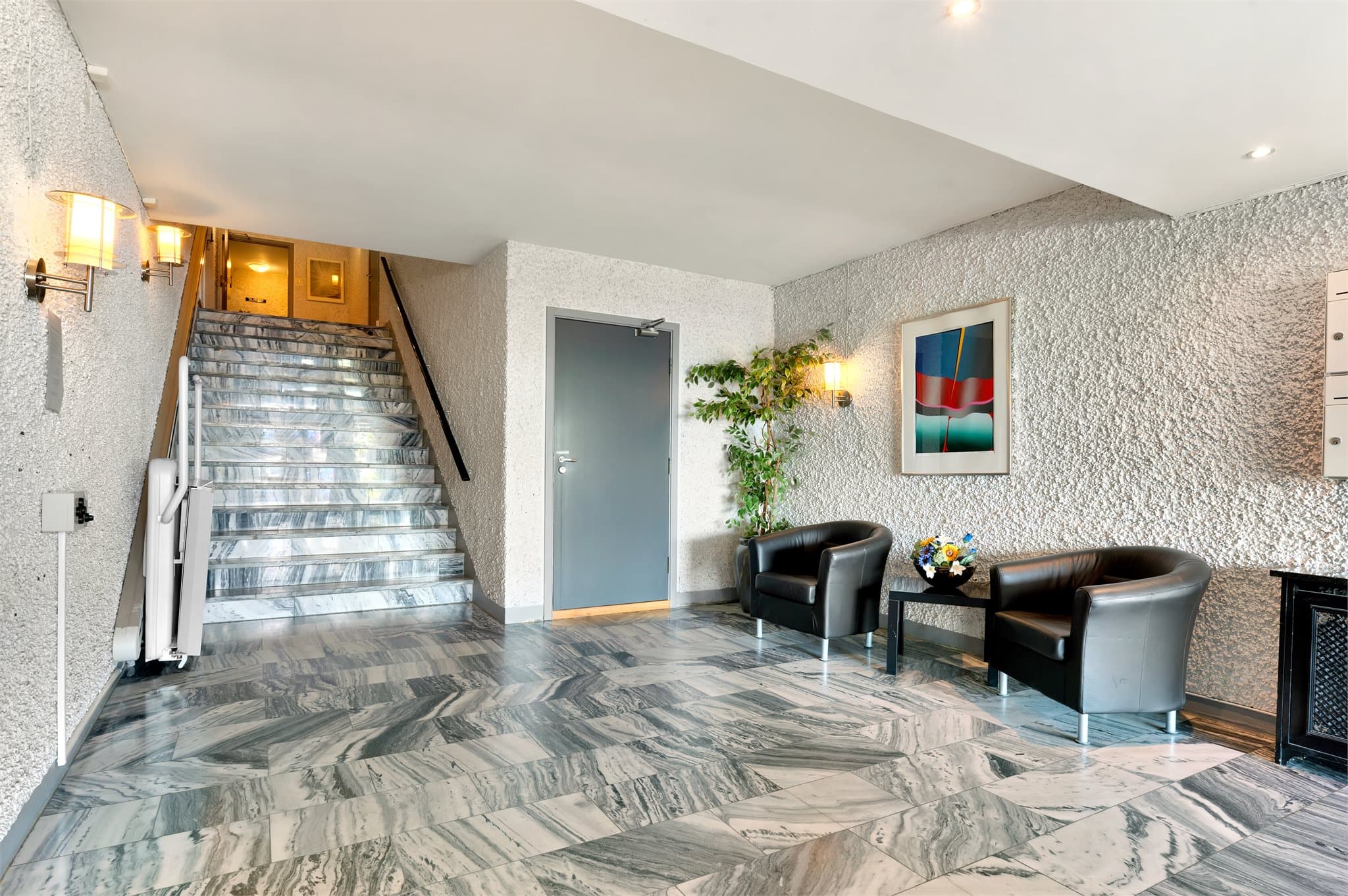 Innbydende, flislagt oppgang med heis.