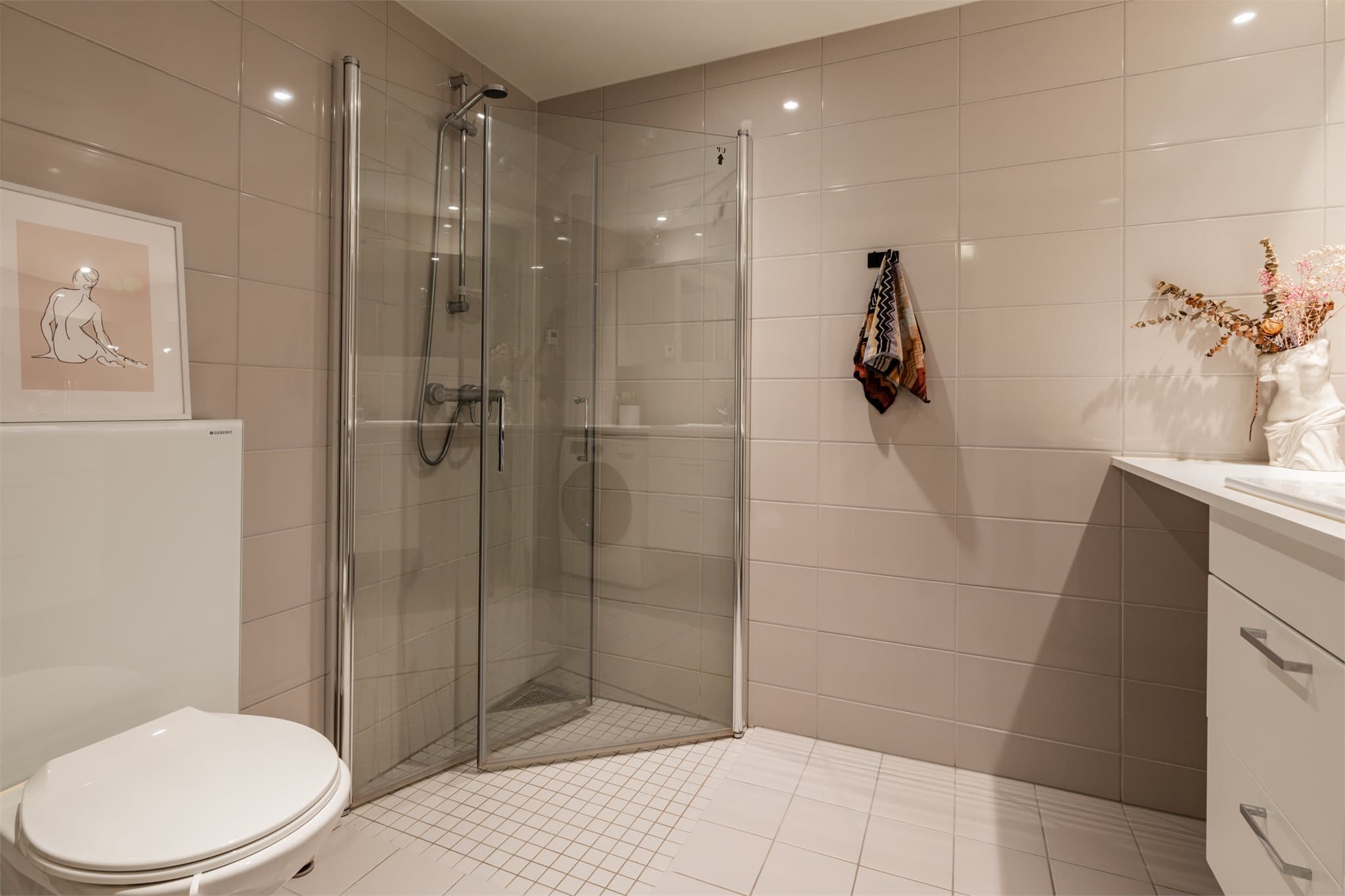 Rommet har et vegghengt toalett og innfellbare dusjvegger som frigjør gulvplass.