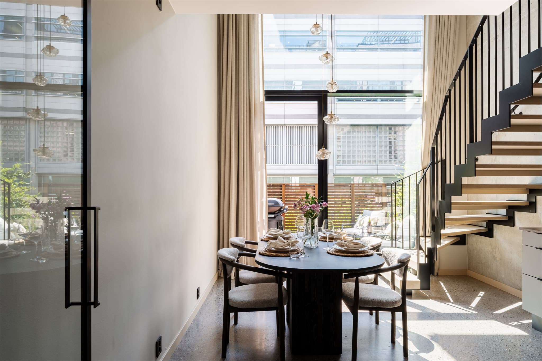 En elegant smijernsdør med sort ramme og glass skiller entréen fra oppholdsrommet, samtidig som den slipper dagslyset fra vindusflaten videre inn i boligen.